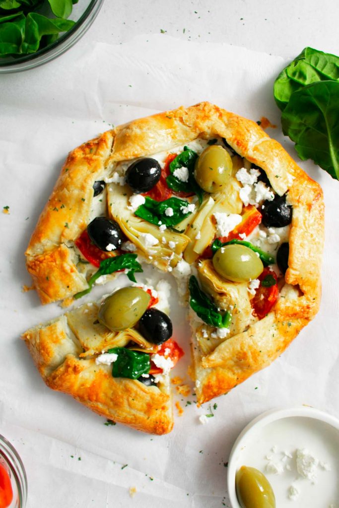 Mediterranean vegetable galette with olives on parchment paper
