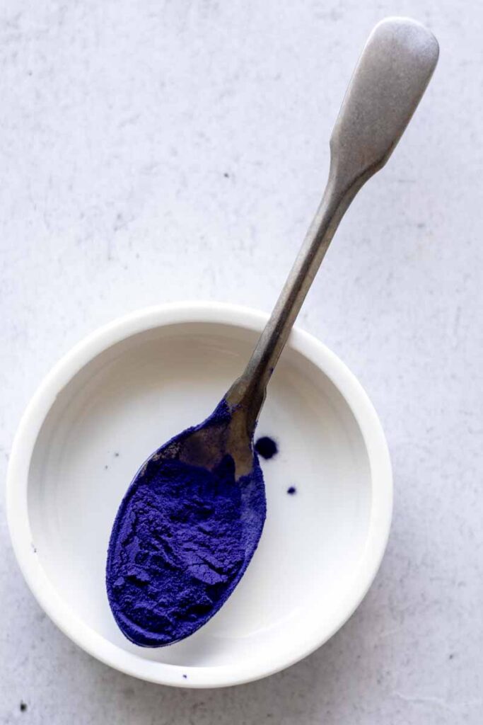 a teaspoon of spoon butterfly pea powder in a small circle plate