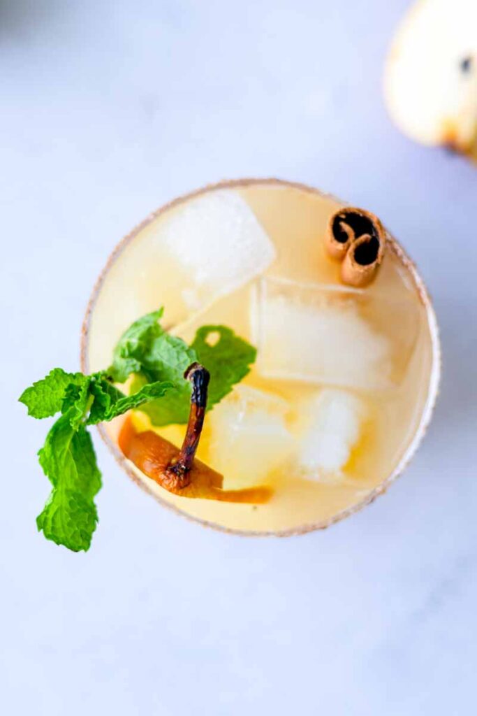 top view of pear ginger beer mocktail with mint leaves, ice and cinnamon stick on a table