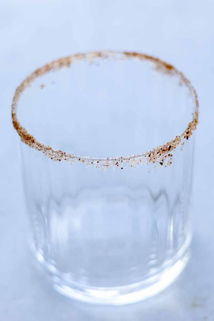 a drinking glass with cinnamon powder and white sugar on the rim