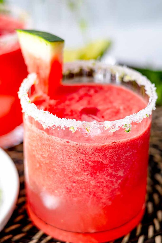 a glass of watermelon mocktail with lime zest and sugar rim and a slice of watermelon for garnish