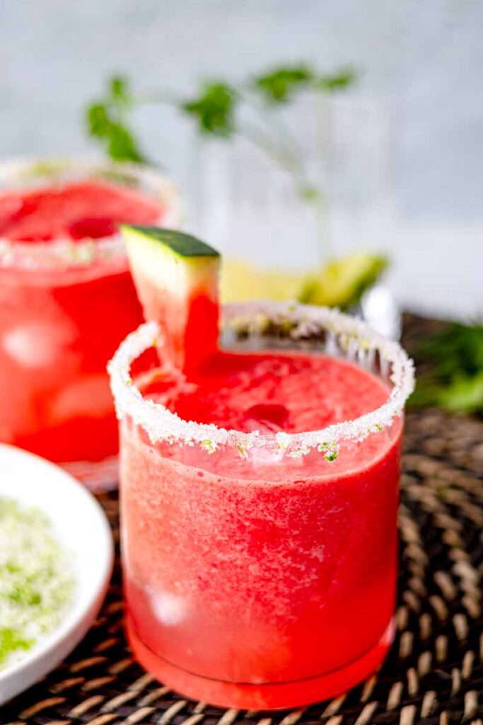 a close up shot  of watermelon mocktail  showing the sugar and lime zest on the glass rim