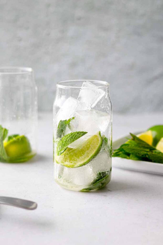a glass with lime juice, crushed mint leaves and ice
