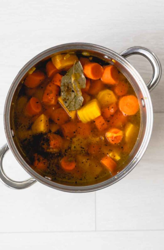 carrot and beets cooking in a pot with broth and spices