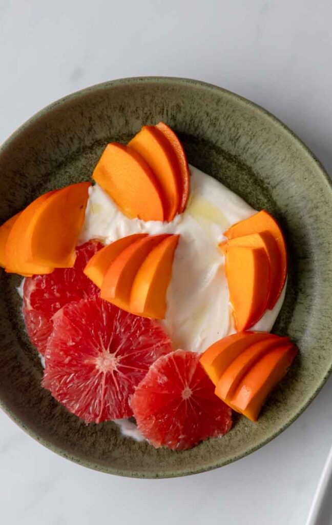 yogurt dressing with wedges of persimmon and slices of grapefruit