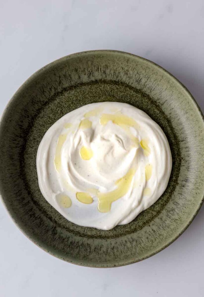 a layer of yogurt dressing on a green plate