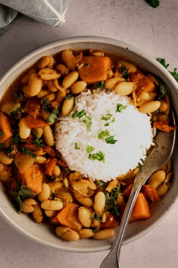 kale sweet potato white bean curry with rice in a bowl
