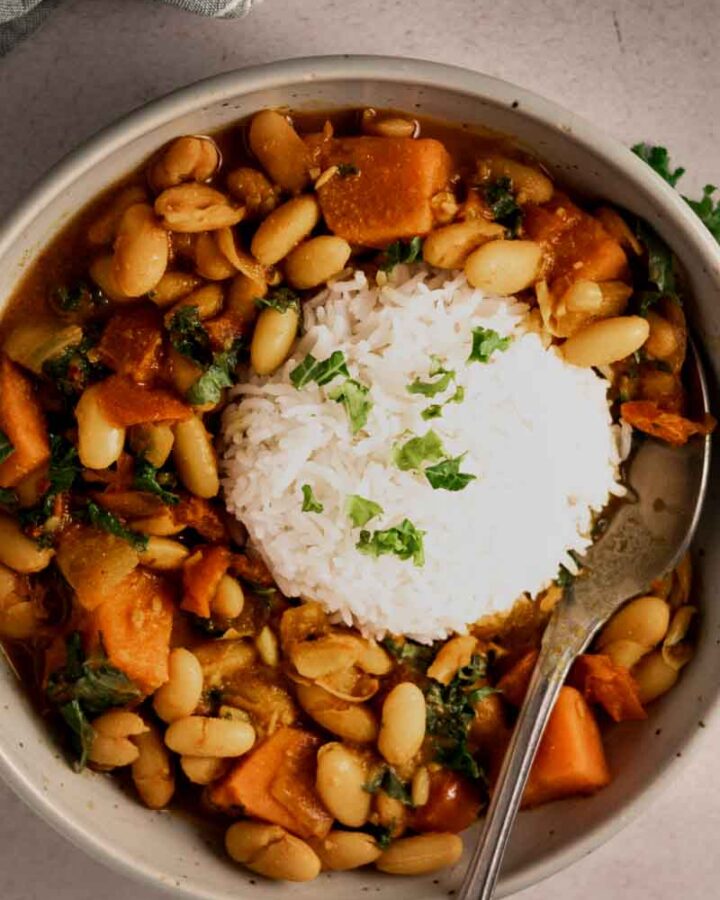 kale sweet potato white bean curry with rice in a bowl