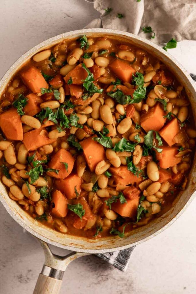 white bean curry with sweet potatoes and kale in skillet