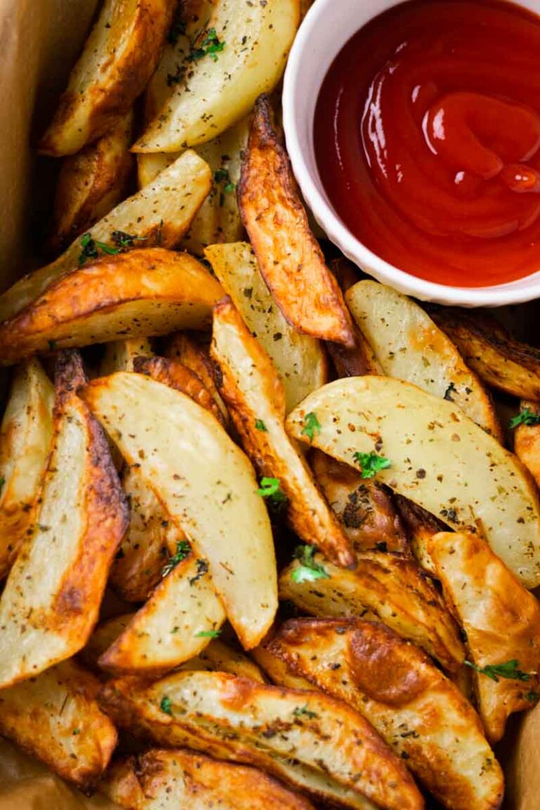 crispy baked potato wedges with a side of ketchup on parchment paper